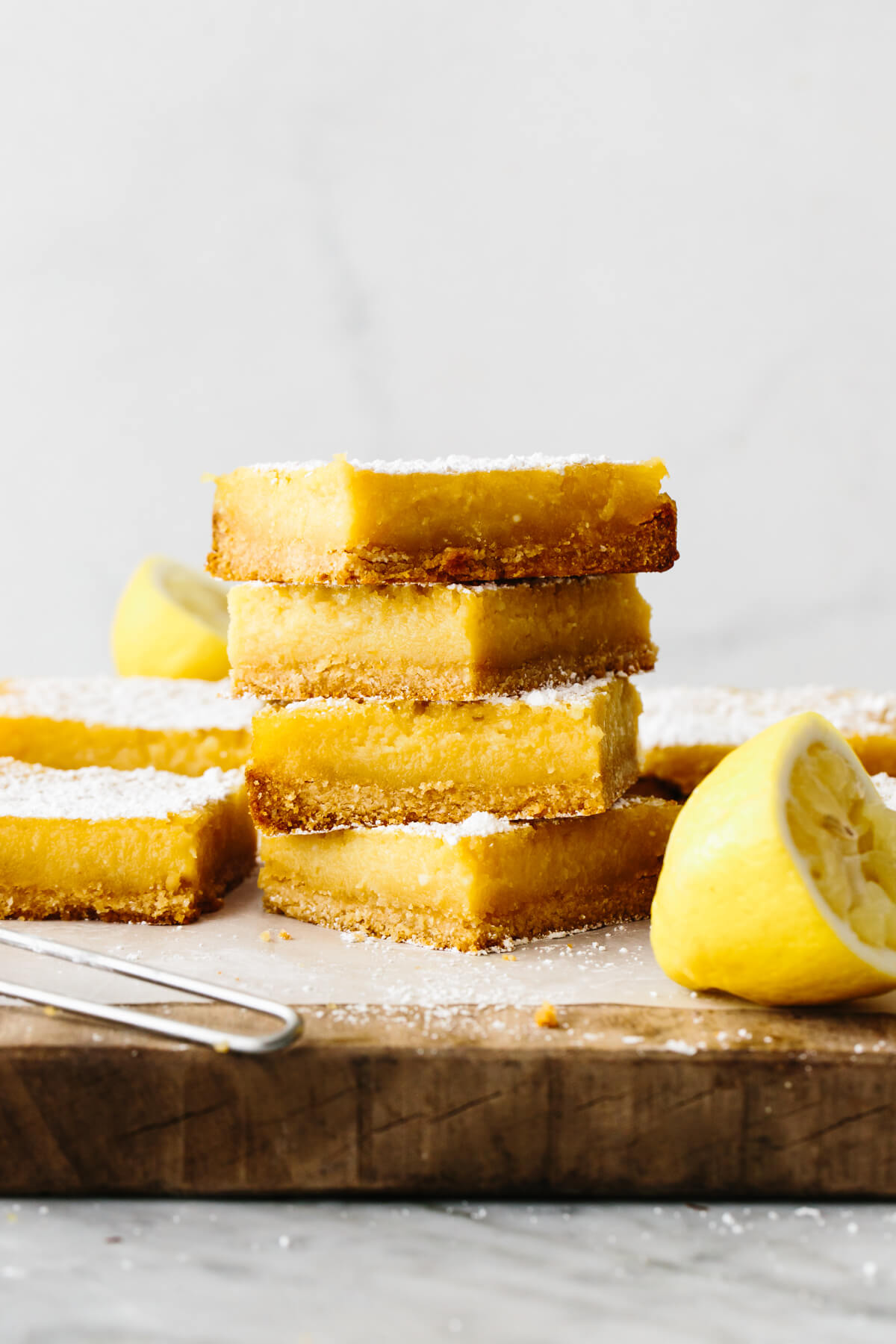 A pile of lemon bars on a wooden board.