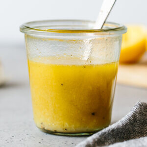 Lemon vinaigrette in a glass jar with spoon.