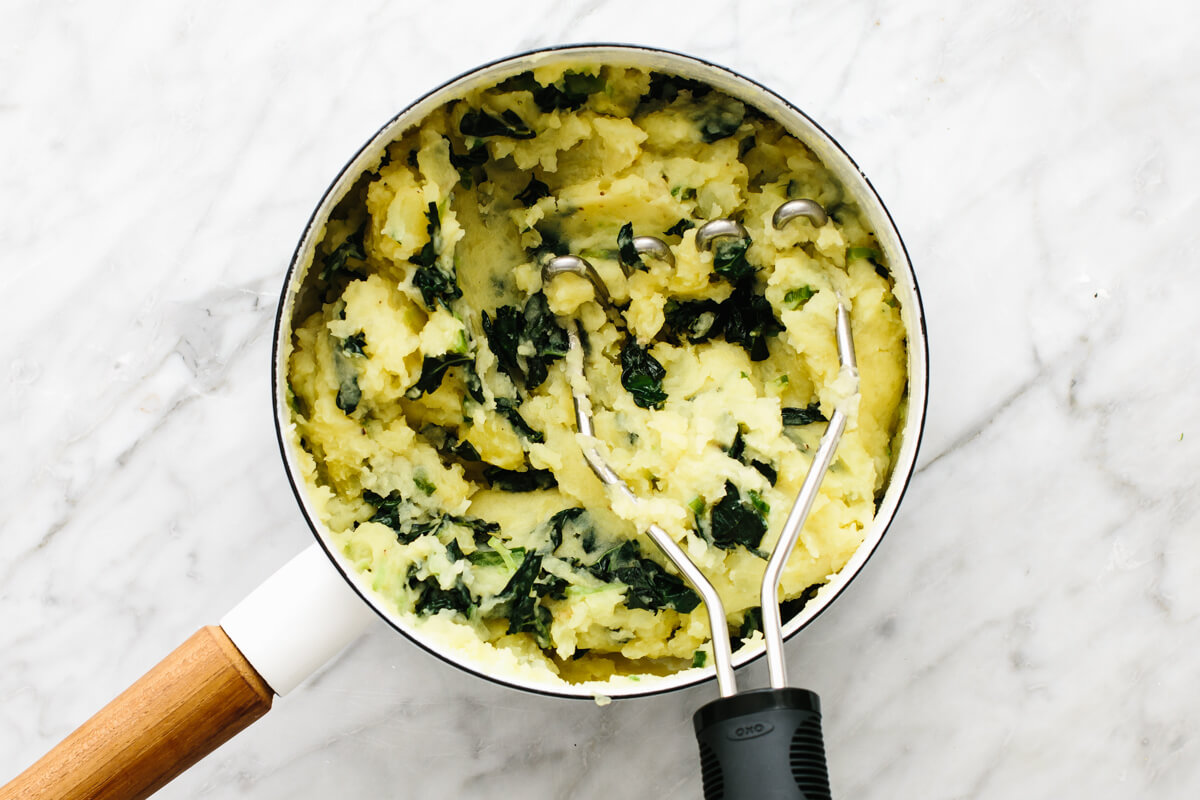 Mixing colcannon ingredients in a pot.