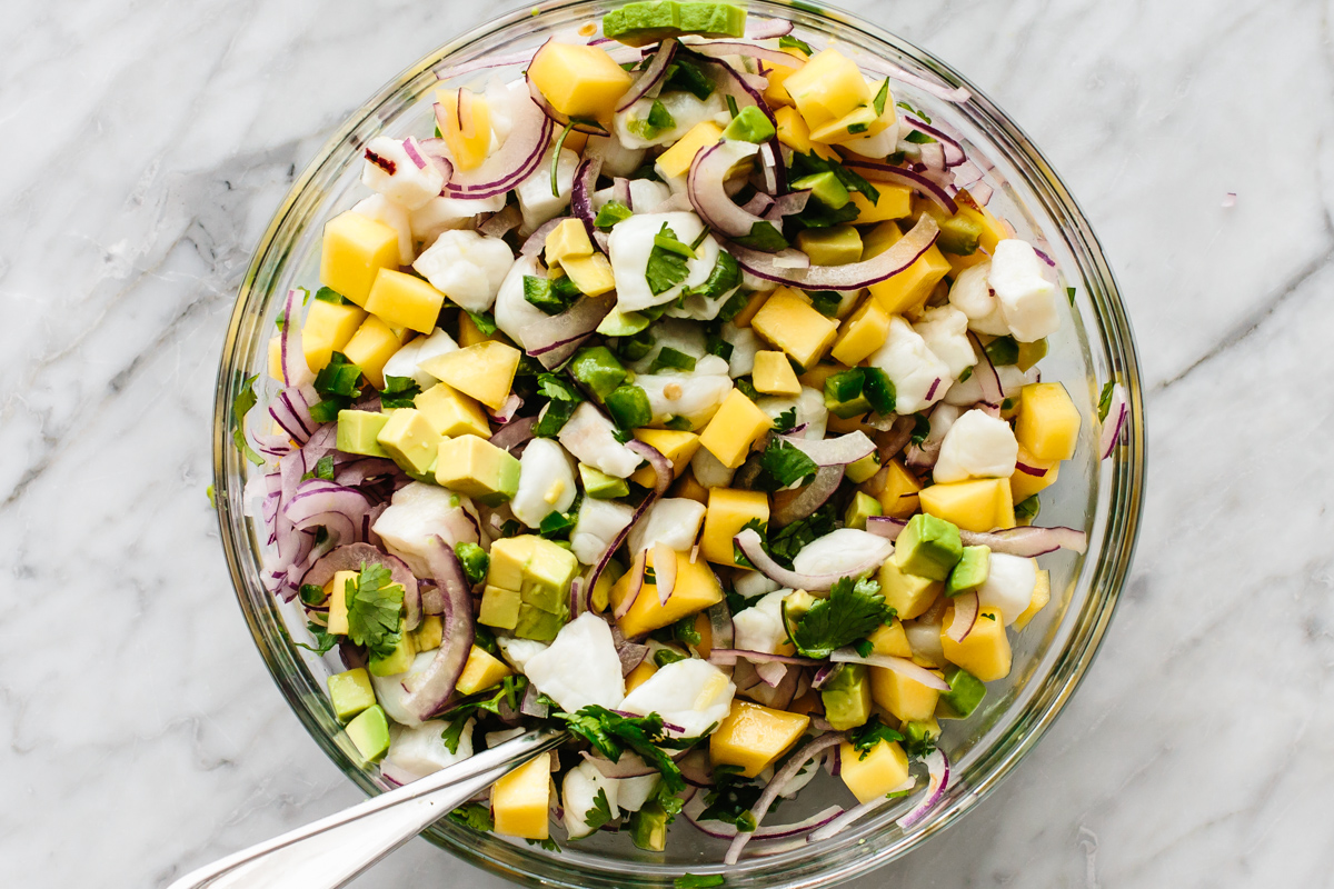 Tossing mango halibut ceviche in a bowl.