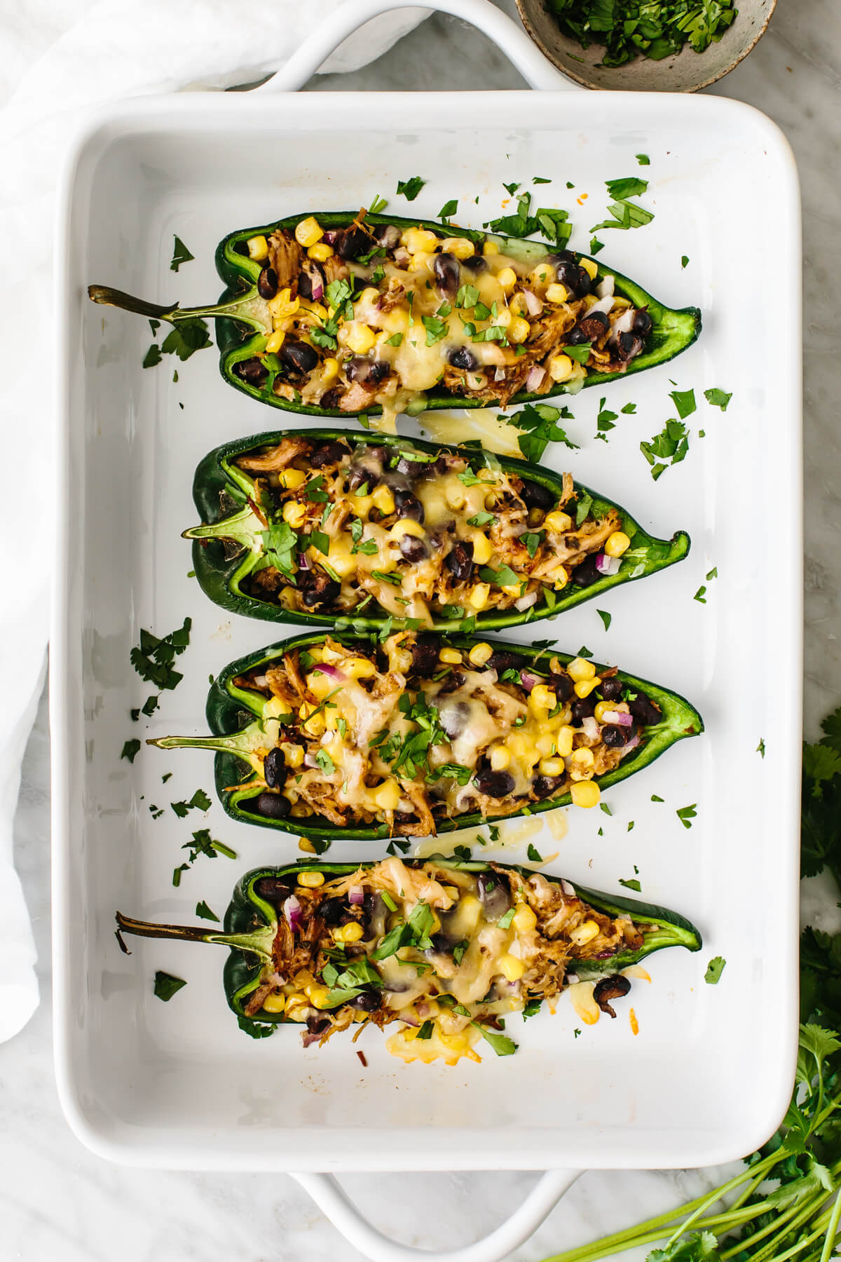 Carnitas stuffed poblano peppers in a baking dish.