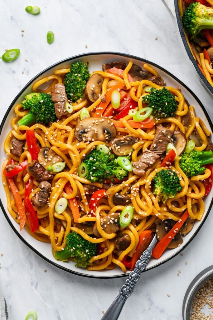 beef lo mein served on a plate and garnished with sesame seeds