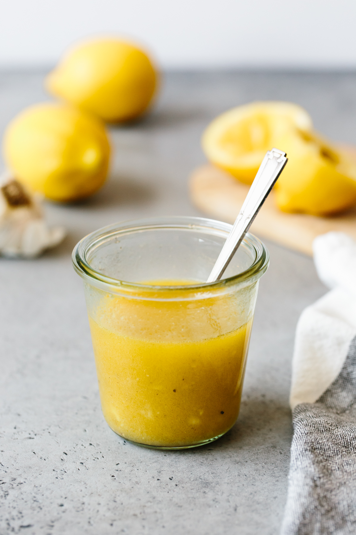 Lemon vinaigrette in a glass jar, with lemons in the background.