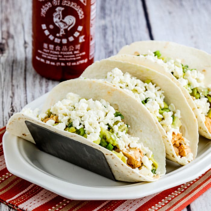 Instant Pot Sriracha Chicken Tacos thumbnail image of finished tacos with Queso Fresca and Sriracha bottled
