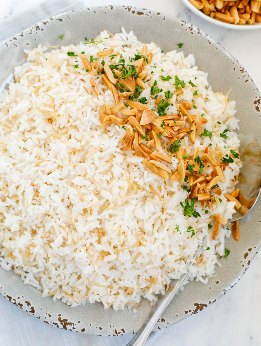top down shot of vermicelli rice served on a plate with toasted almonds on top.