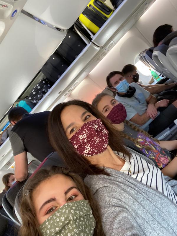 A family of 4 sitting in an airplane wearing their face masks. 