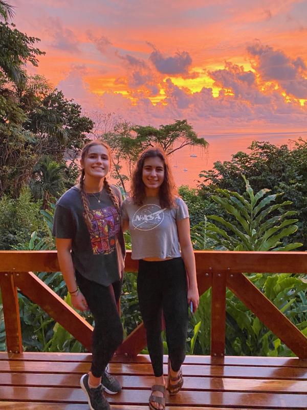 Two sisters posing with a gorgeous sunset and ocean in the background. 