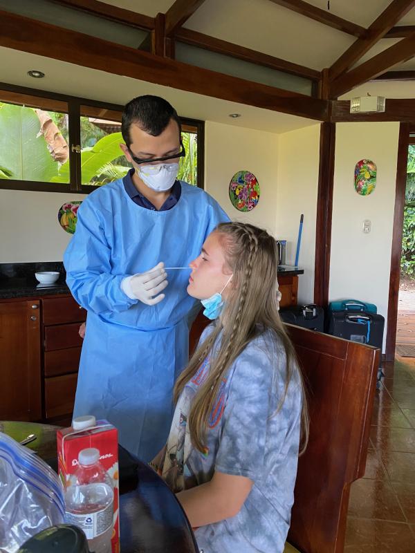Girl receiving a COVID test by a doctor in blue scrubs. 