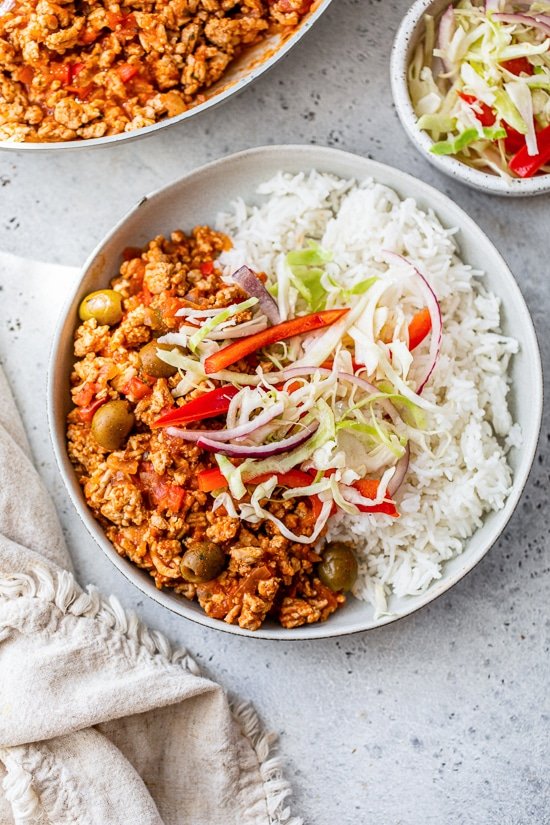 Picadillo with rice and slaw on a plate.