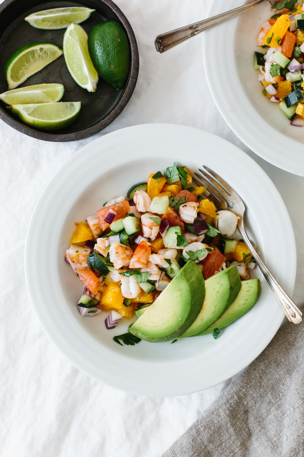 Shrimp ceviche in a white bowl and topped with avocado.