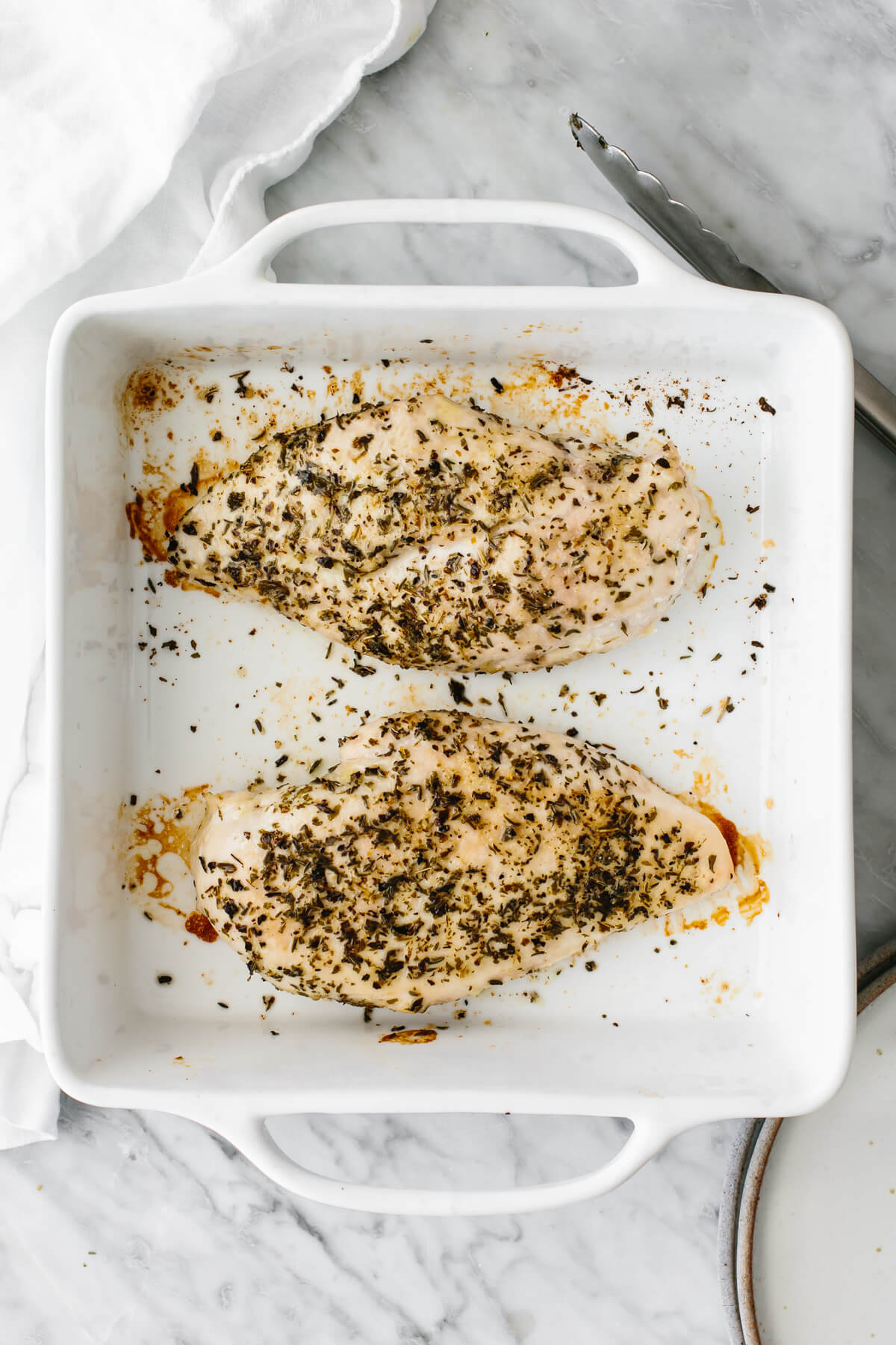 Herb baked chicken breasts in a baking dish.
