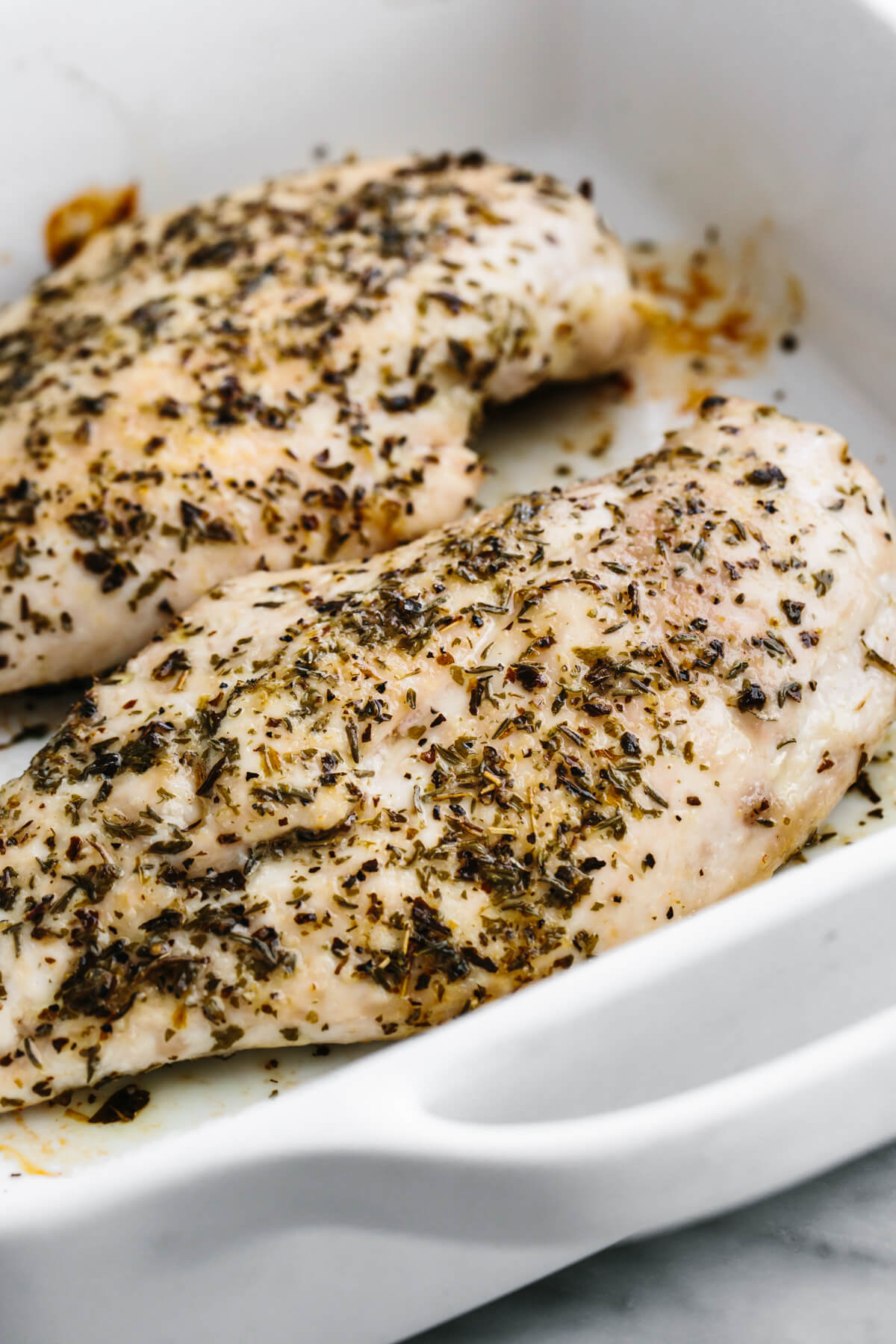 A baking dish with herb baked chicken breasts.