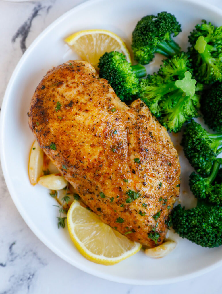 Close up of a chicken breasts beside broccoli florets.