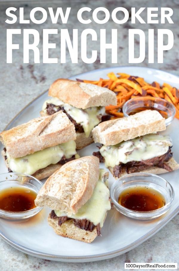 Four French Dip sandwiches on a plate with small bowls of au jus and a side of sweet potato fries. 