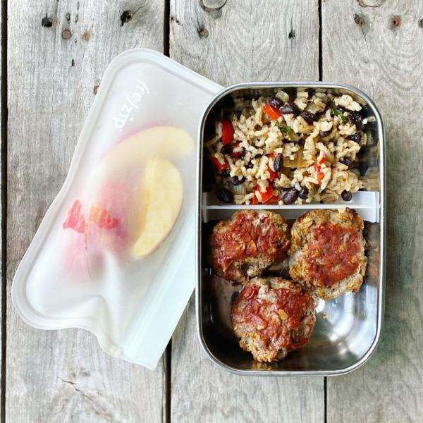 Packed school lunch that includes mini meatloaves with rice and beans, and apple slices. 