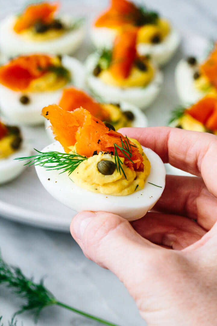 Holding a single smoked salmon deviled egg in hand.