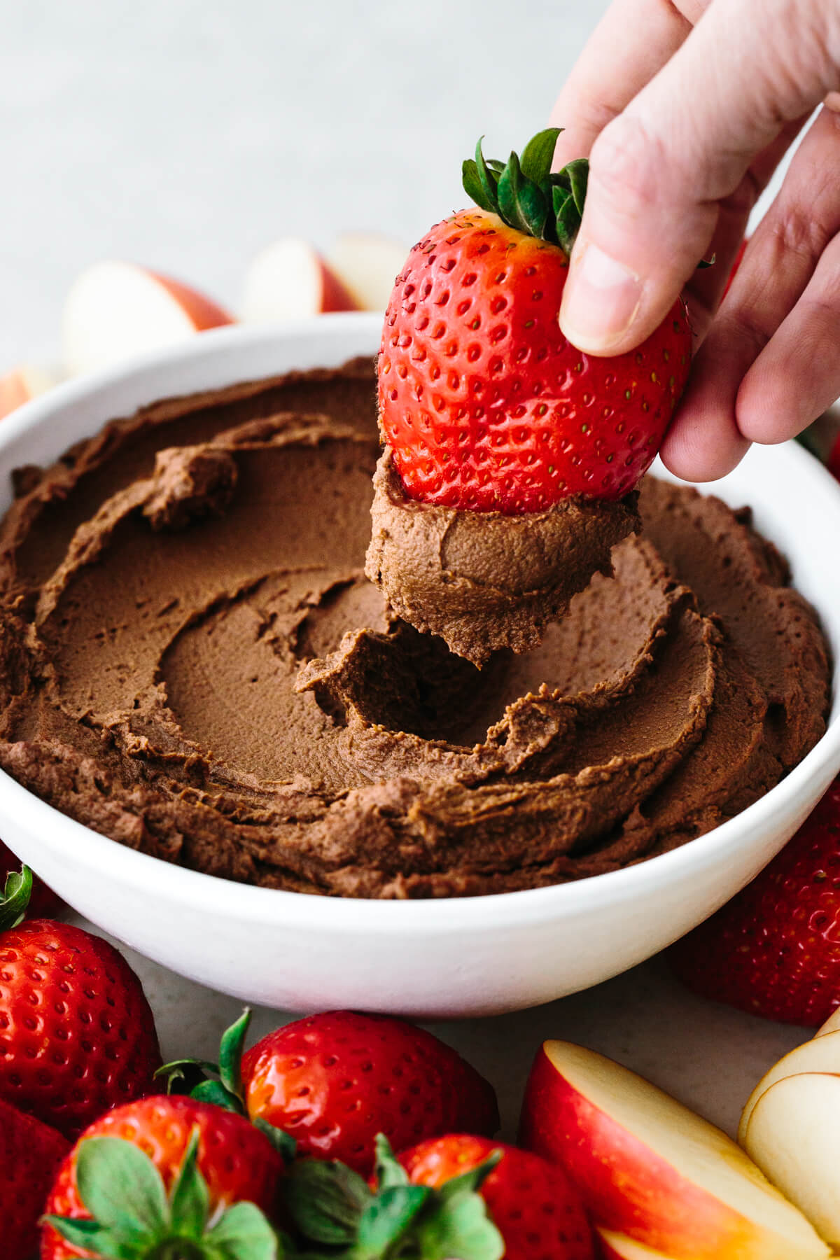 Dipping a strawberry into chocolate hummus.