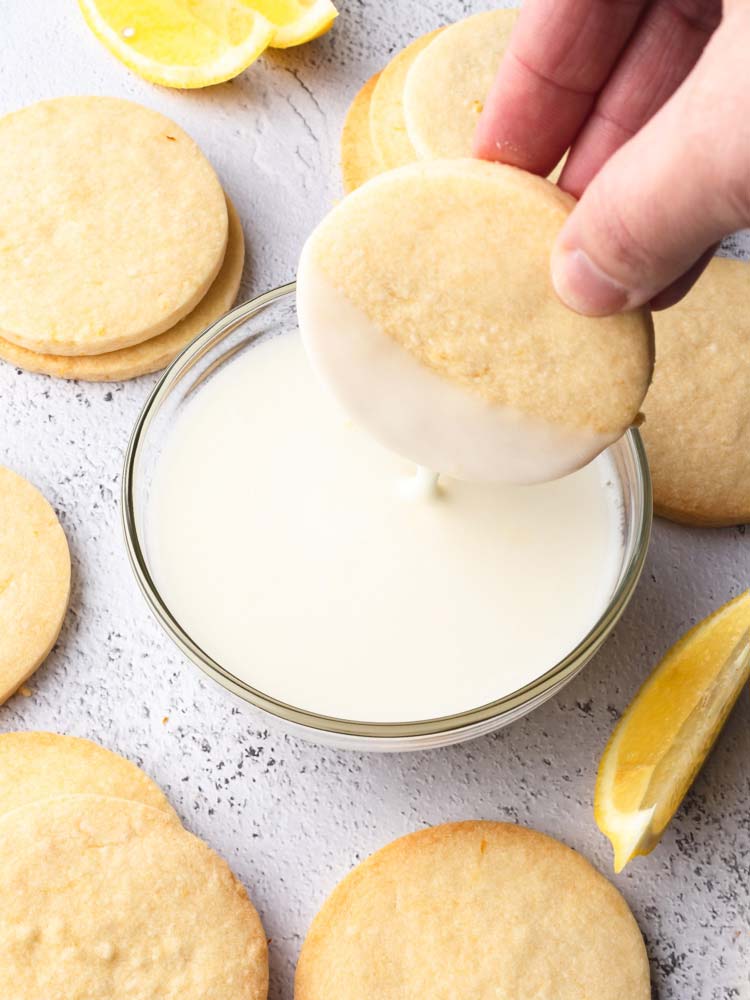 cookie being dipped half way into lemon icing