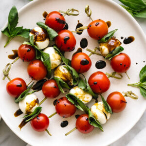 A plate of caprese skewers with basil leaves