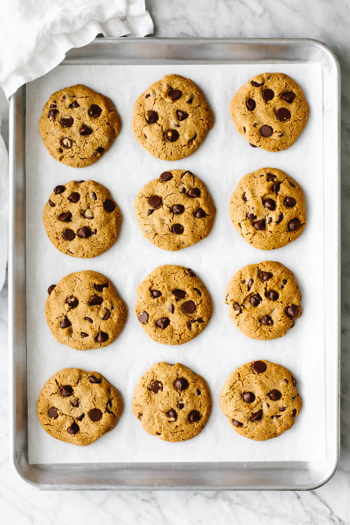 A metal sheet pan with gluten-free chocolate chip cookies lined up.