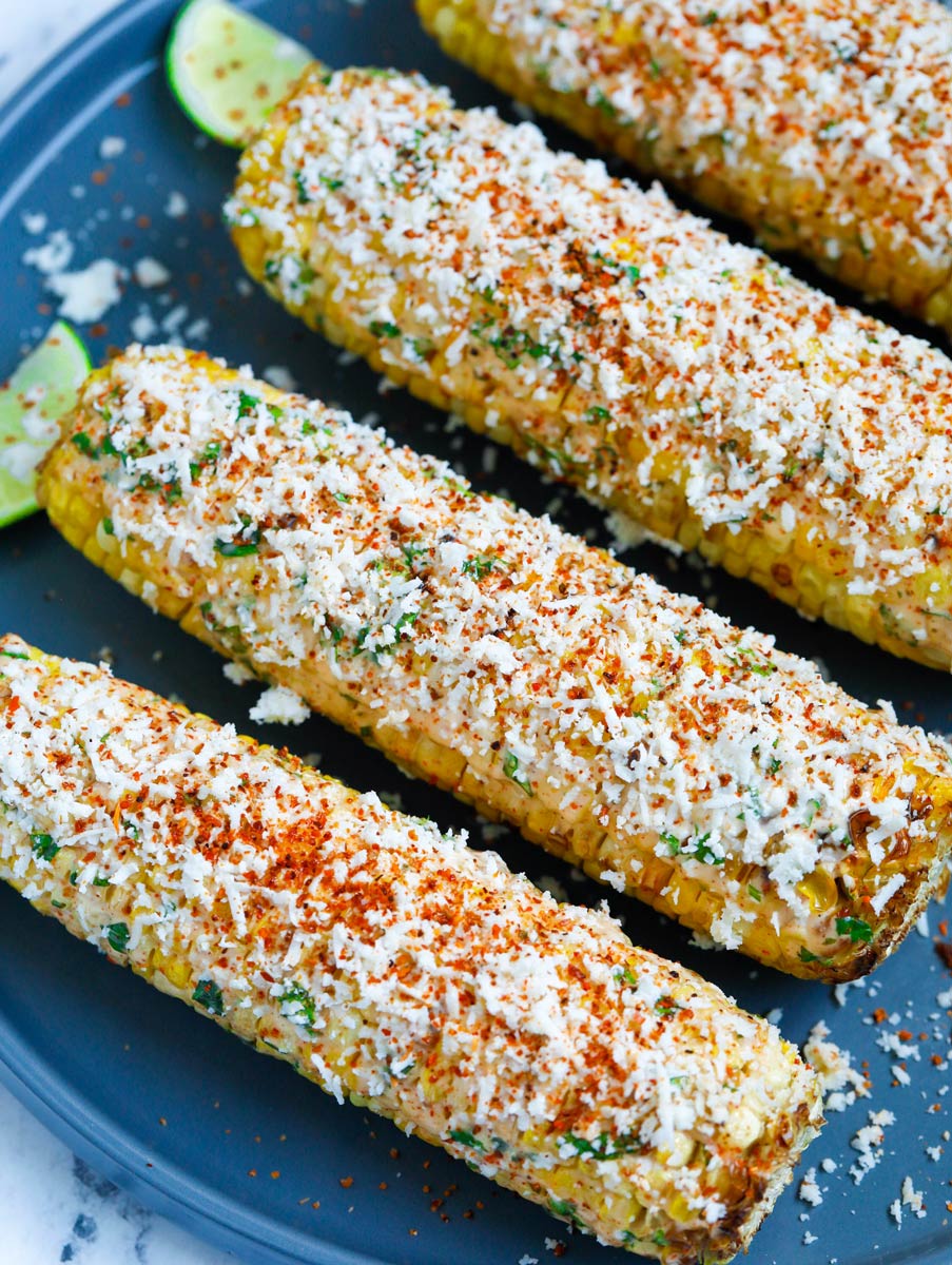 Mexican street corn on a plate with cotija cheese and tajin on top.