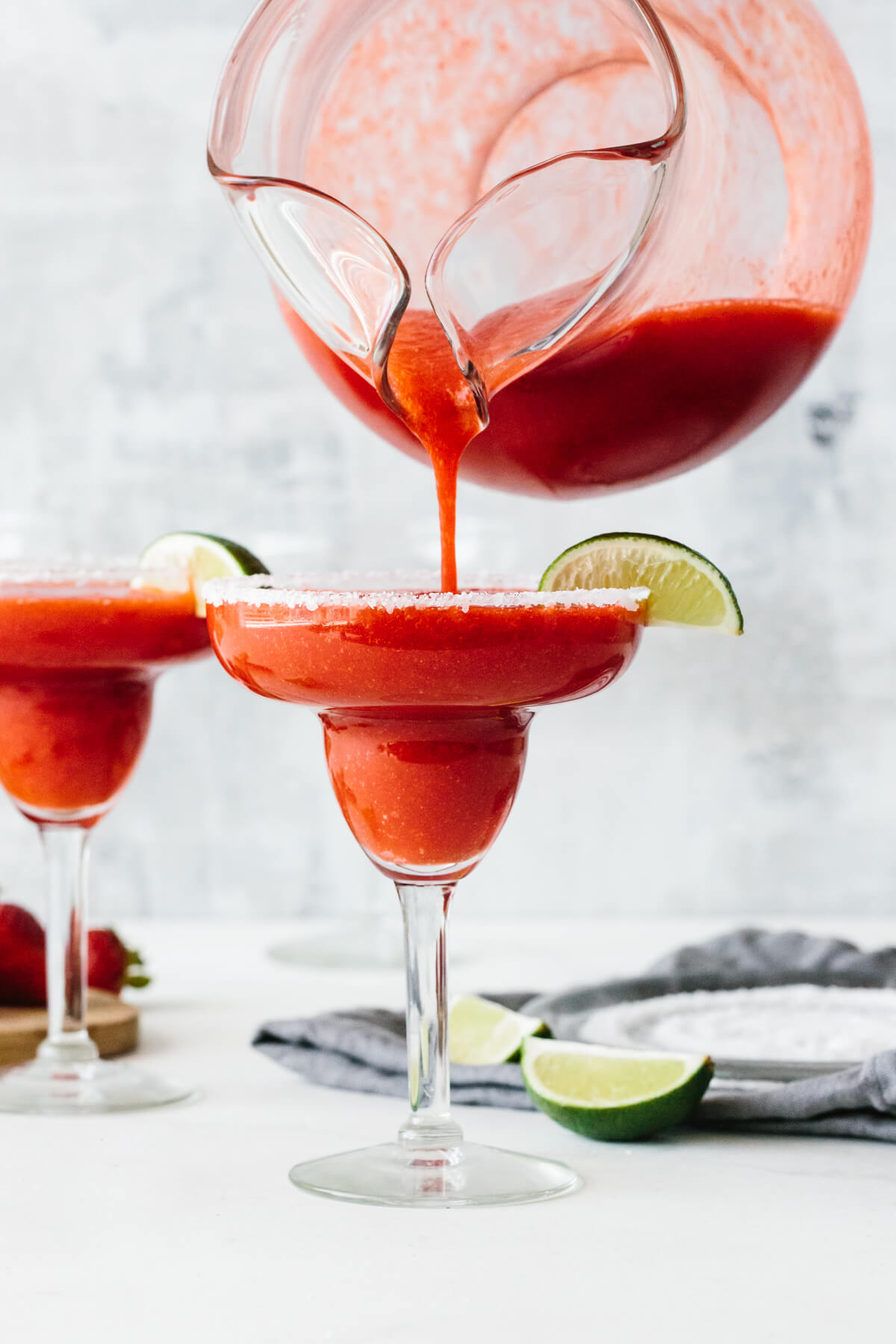 Pouring strawberry margarita into a glass.