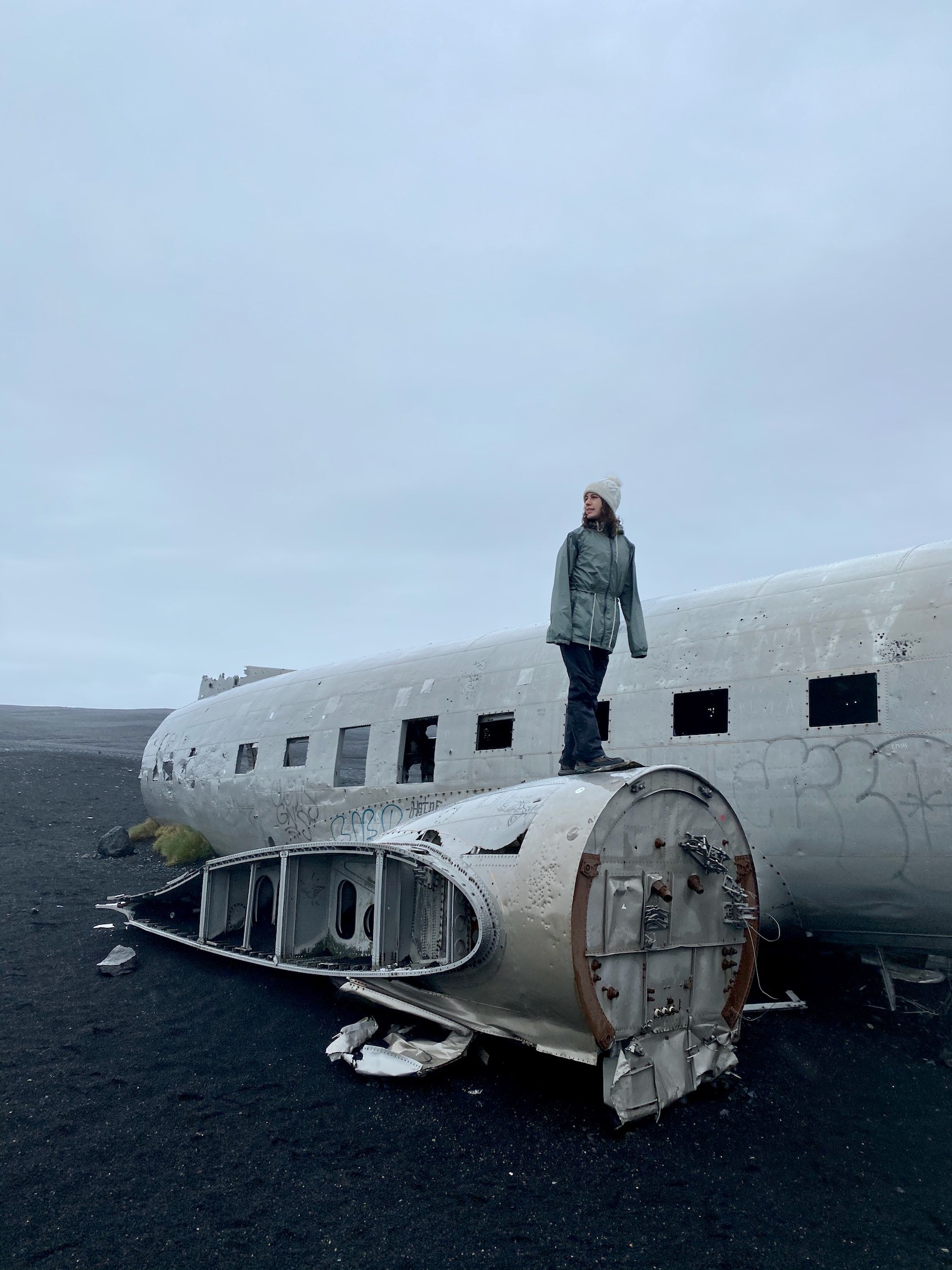 Teen girl standing on top of the famed 1973 plane wreck in Iceland. 