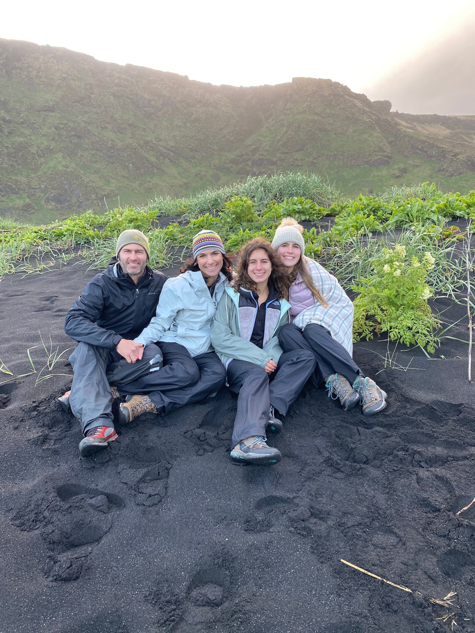 Family posing on black beach in Iceland. 