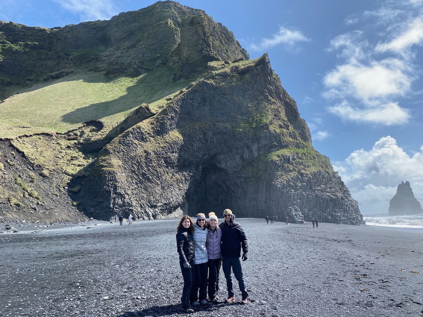 Family posing on beach in front of Basalt Columns in Iceland. 