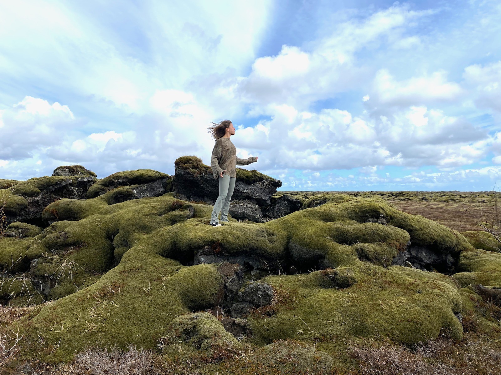 Teen girl standing on moss covered mounds in Iceland. 