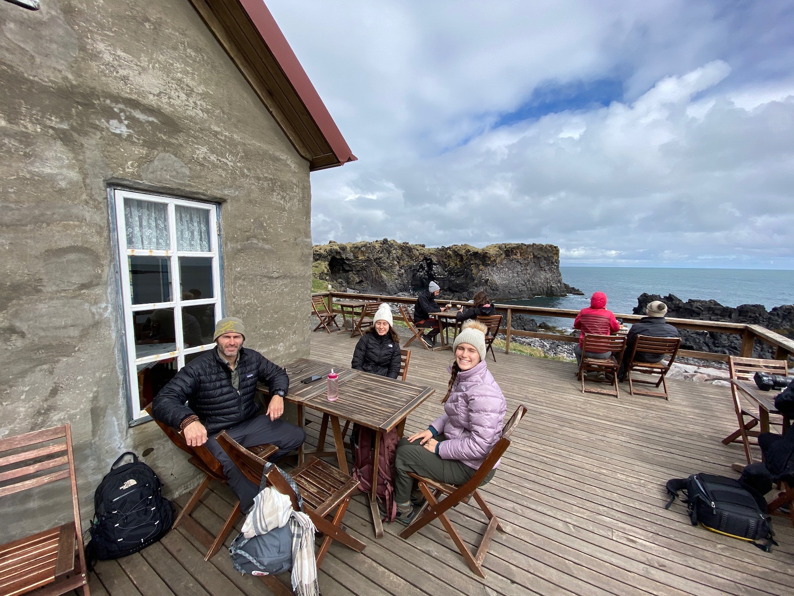 Family sitting at a table outside a cafe overlooking scenic views in Iceland. 