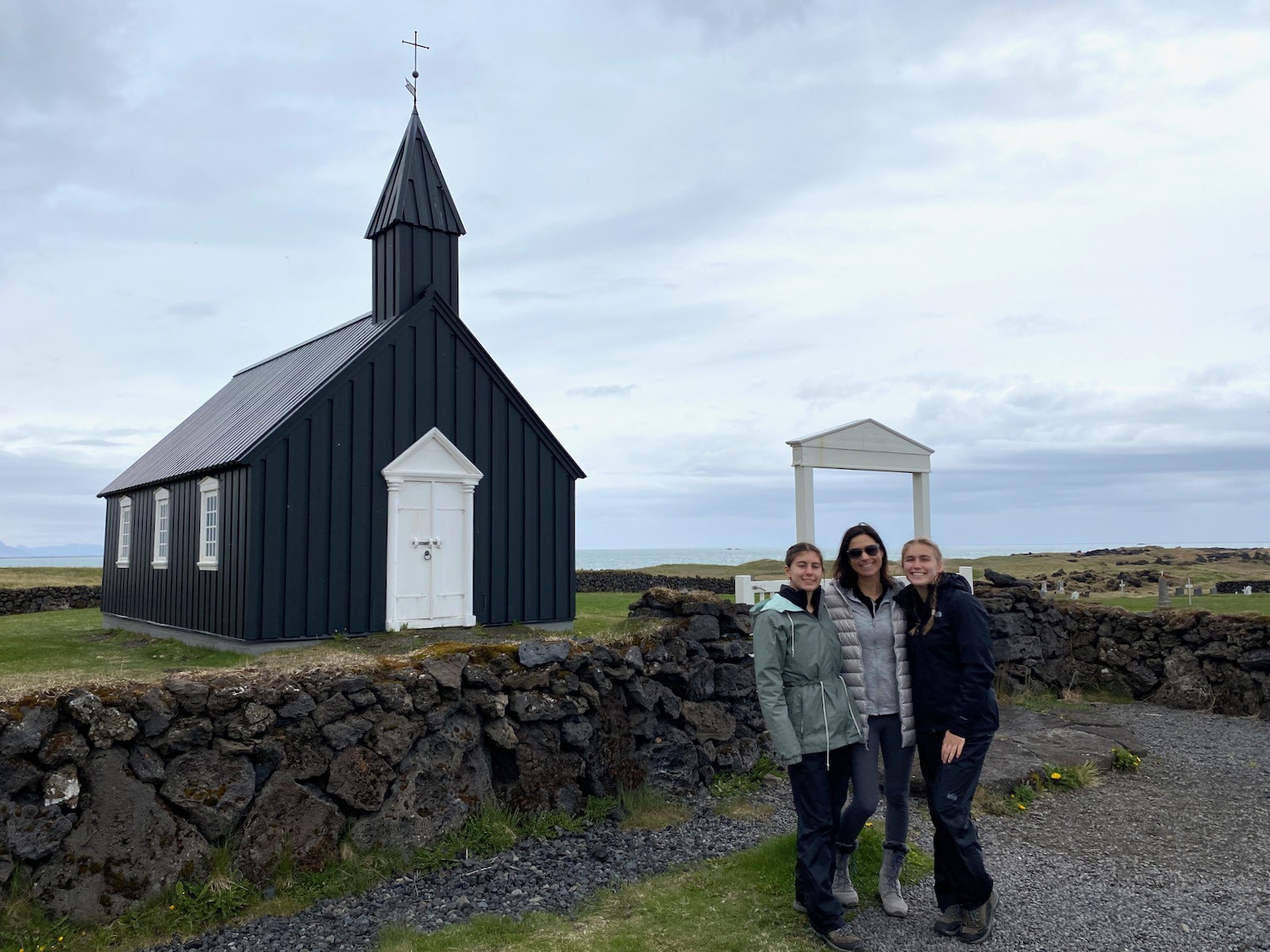 Mother and two daughters posing in front of a quaint little church in Iceland. 