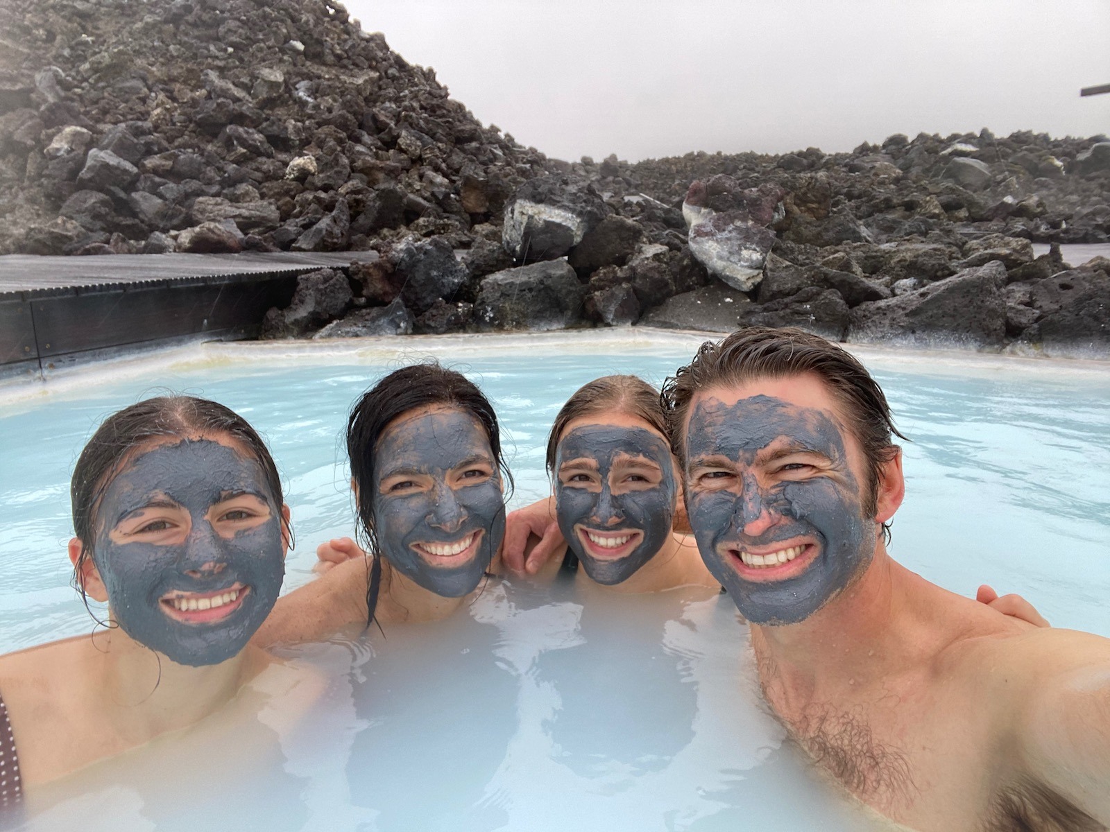Family posing with mud masks on in the Blue Lagoon in Iceland. 