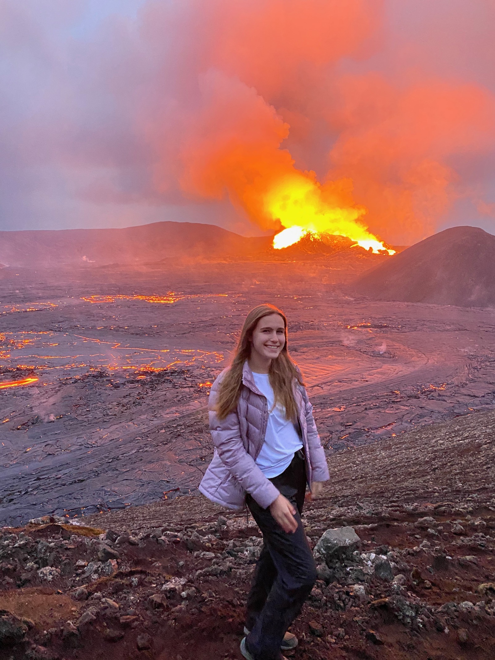 Teen girl posing in front of the erupting Fagradalsfjall Volcano. 
