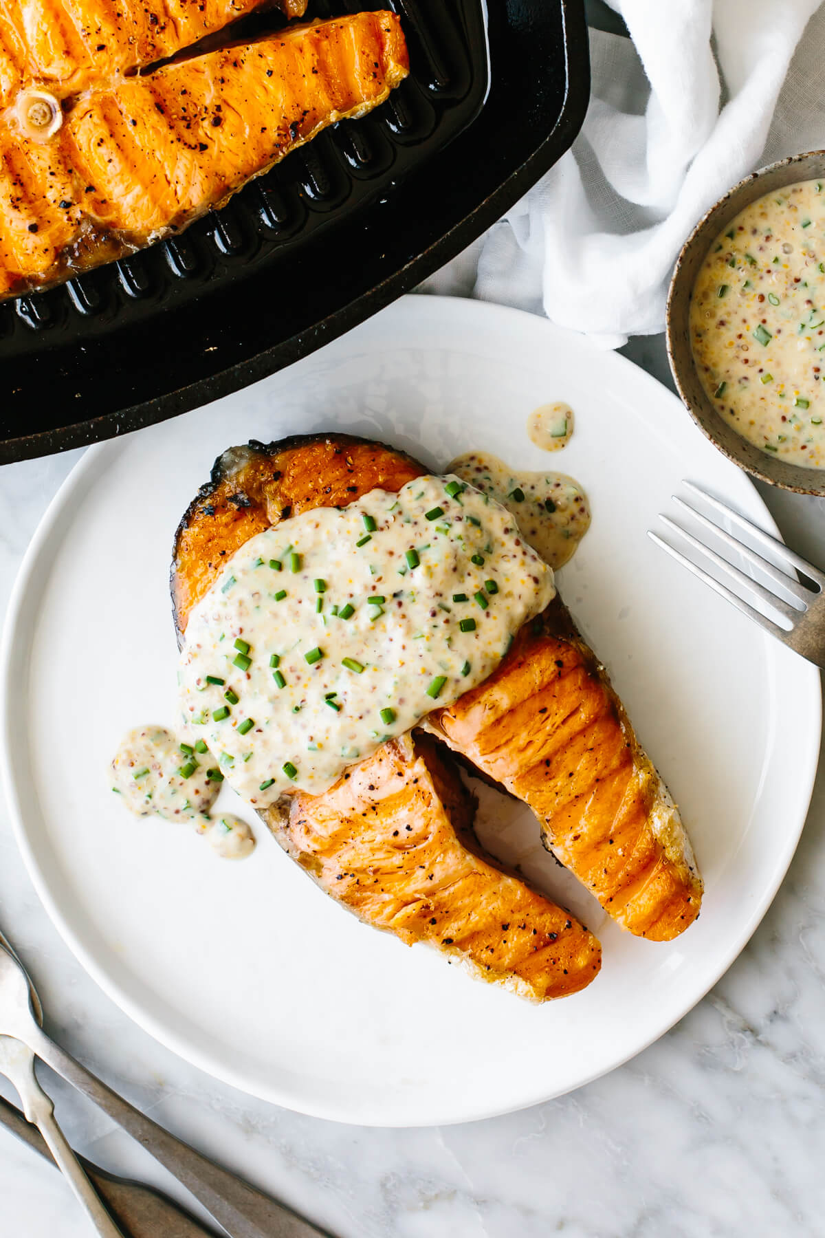 Grilled salmon steak on a plate next to a skillet