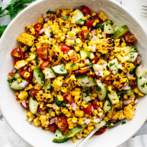 A large white bowl of corn salad next to parsley and a napkin