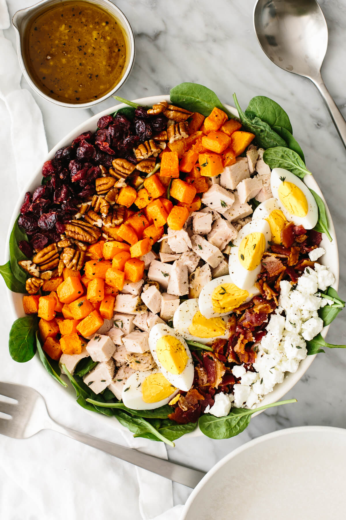 Turkey cobb salad in a large bowl on a table next to a spoon.