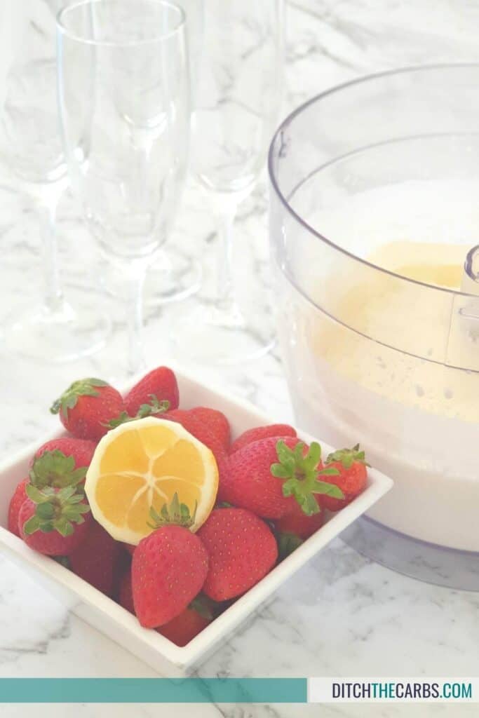 whipped cream in a food processor with strawberries in a bowl