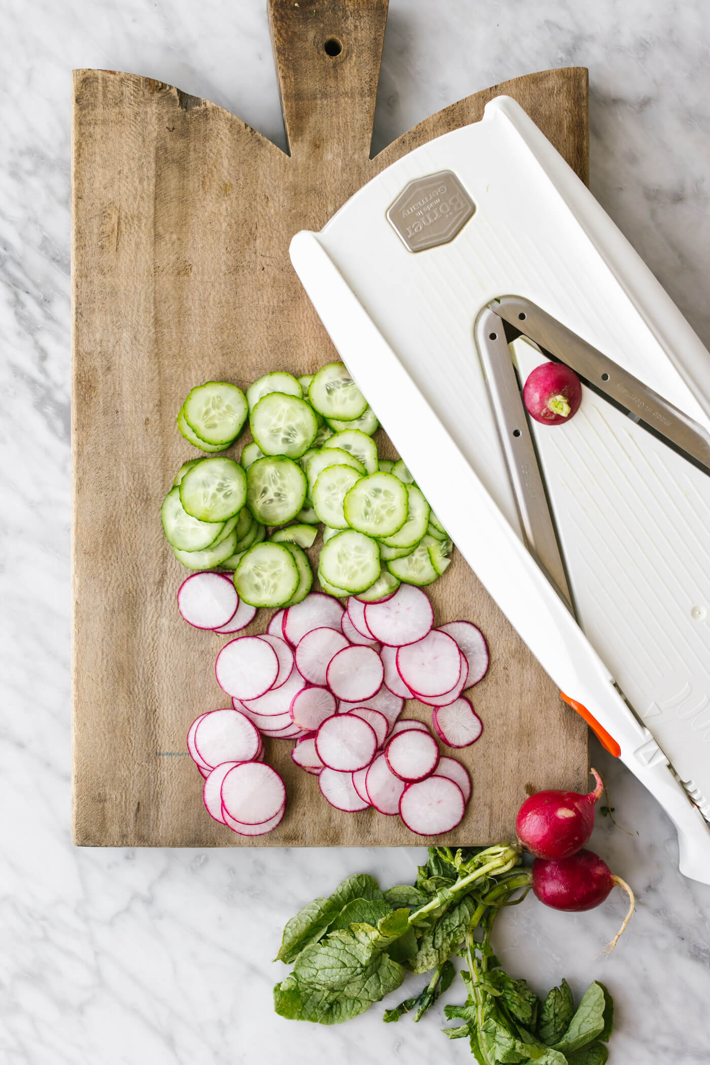 Slicing cucumbers and radish with a mandolin for a salad.