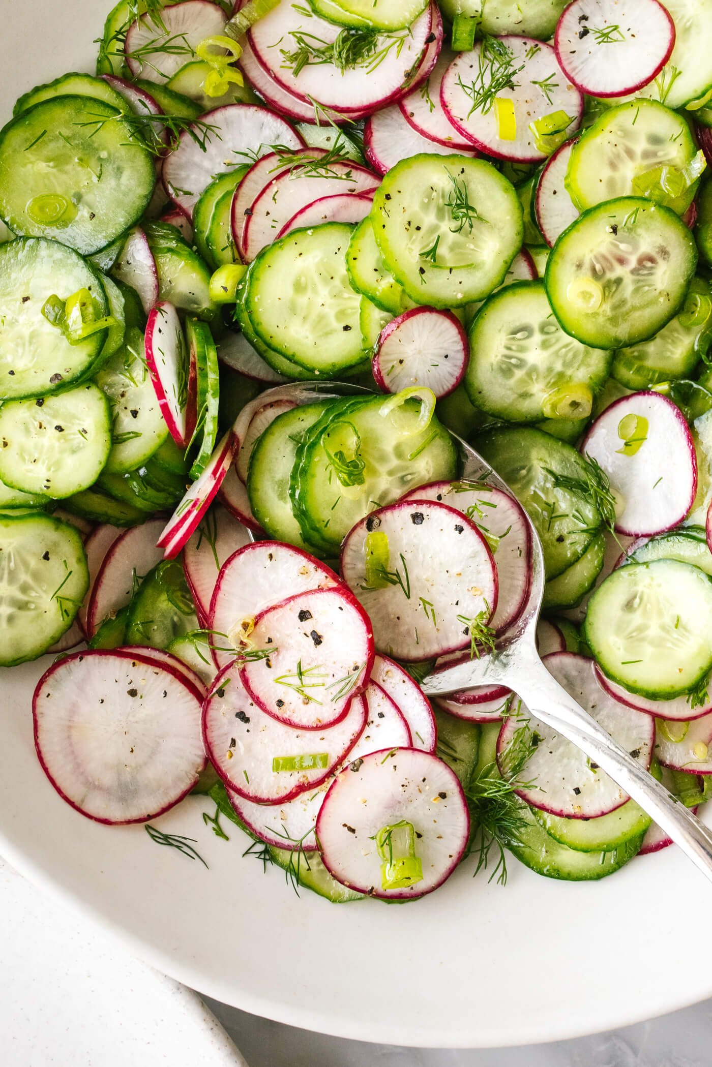 A bowl of cucumber radish salad with a spoon