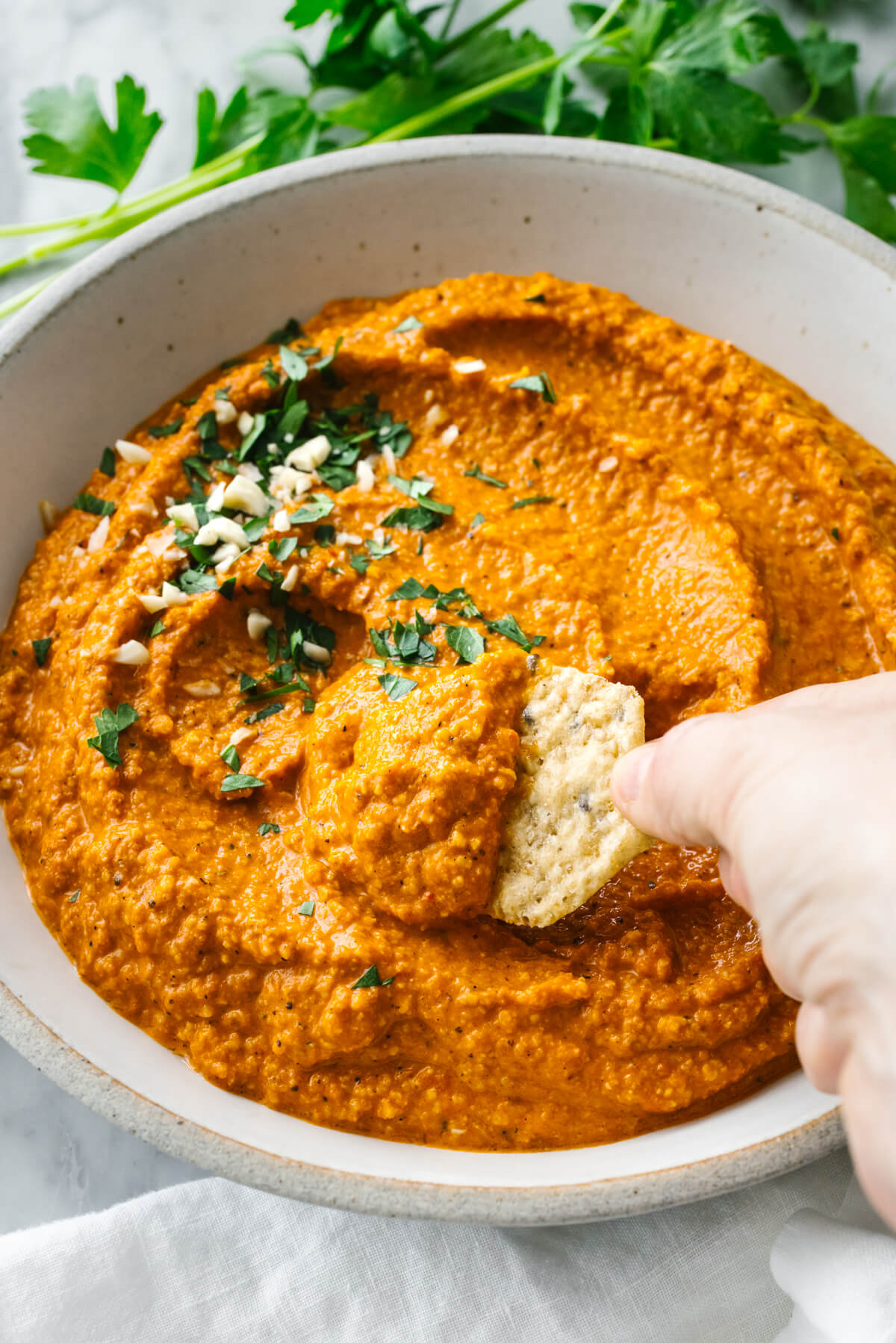Dipping into a bowl of romesco sauce with a cracker
