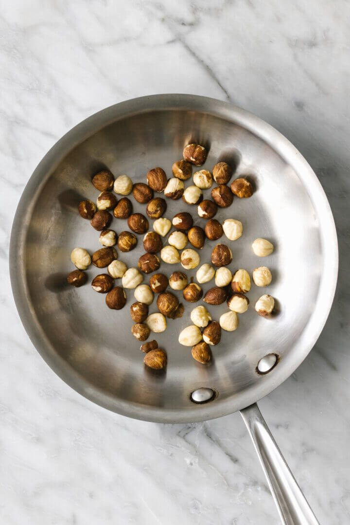 Toasting hazelnuts in a pan for romesco sauce