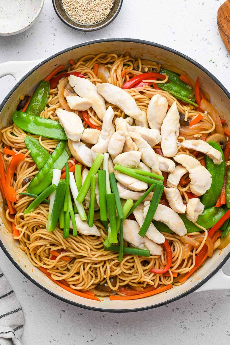 chicken and veggies in a skillet on top of the lo mein noodles
