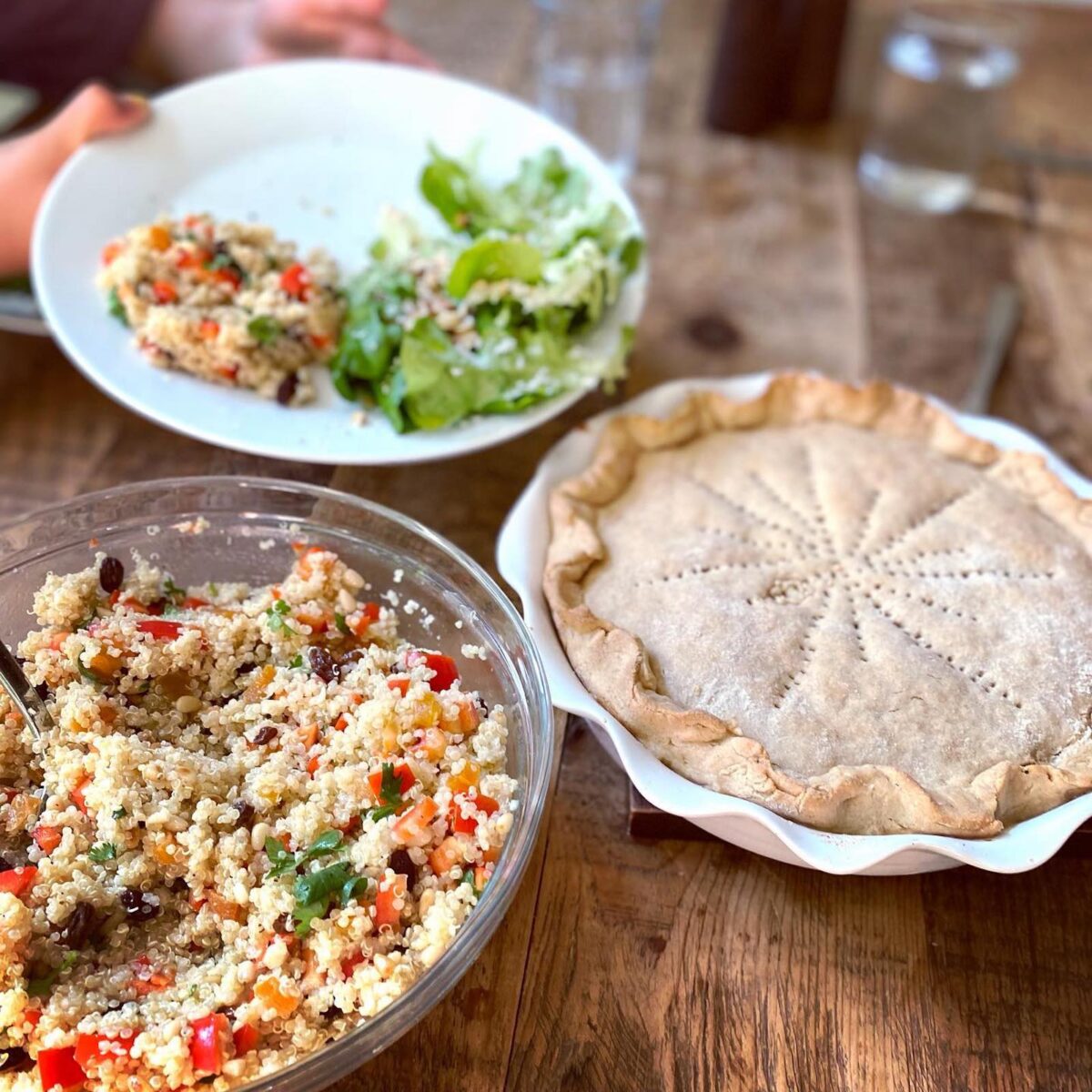 A Tomato Pie in a dish with a bowl of couscous salad on the dinner table. 