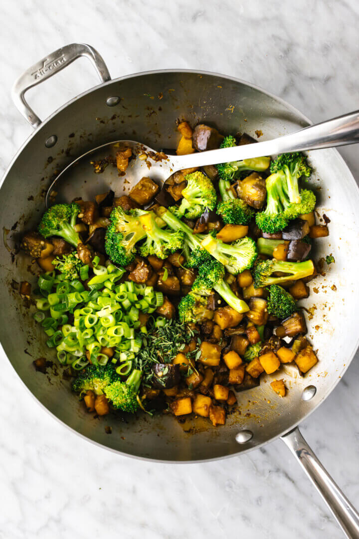 Stir fry veggies in a wok including butternut squash, broccoli, and eggplant
