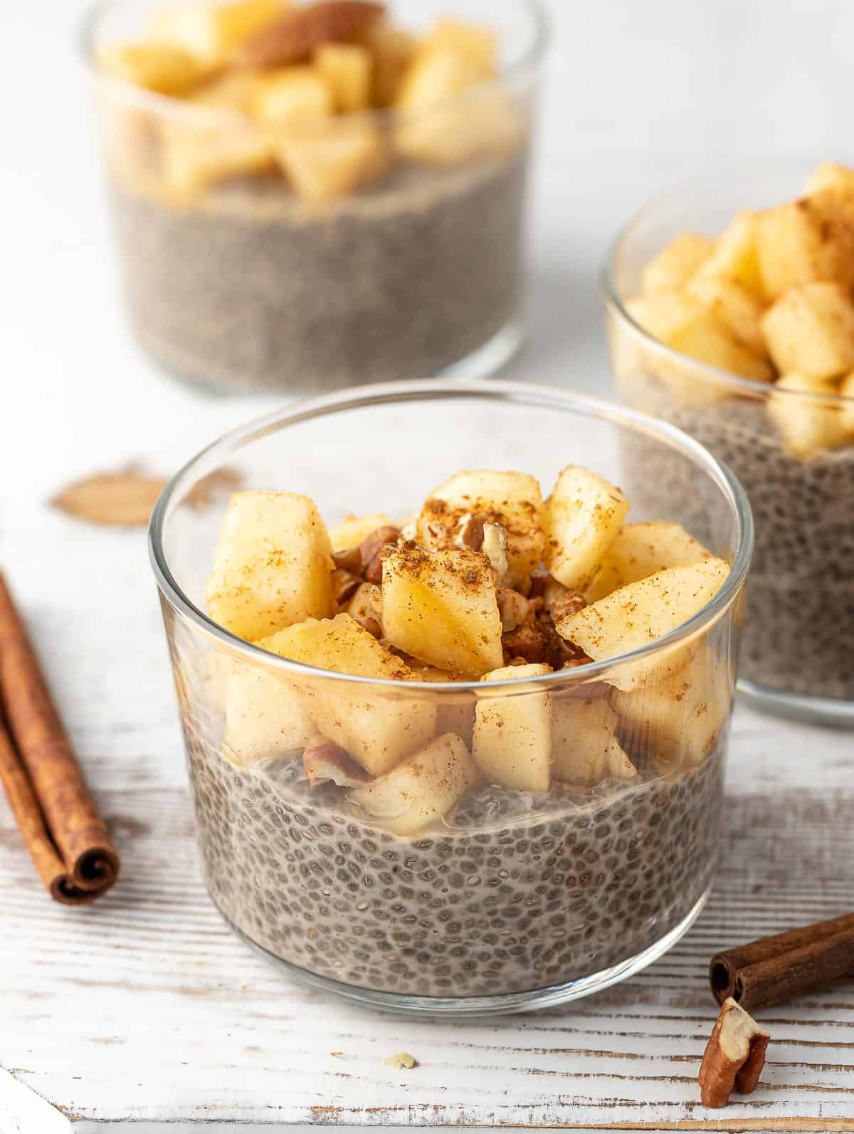 Overnight Chia Pudding topped with apples and cinnamon sticks on the side of the bowl.