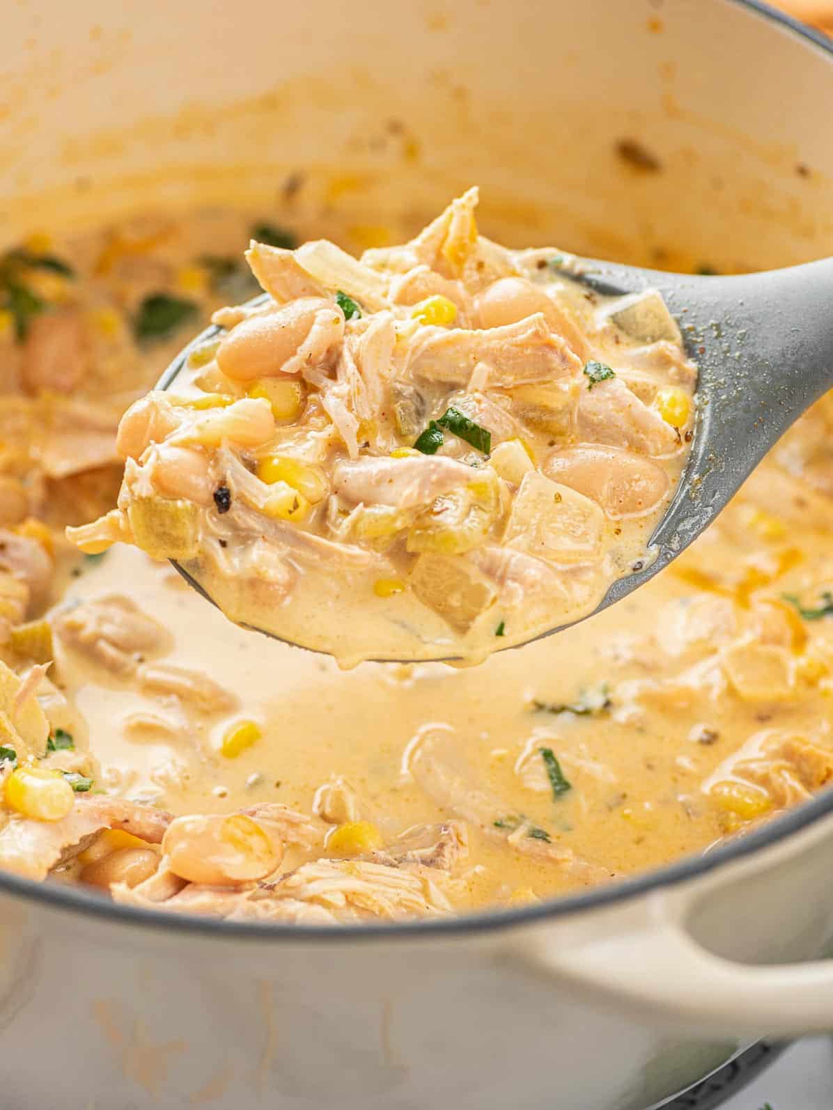 a spoon of white chicken chili scooped out of the pot