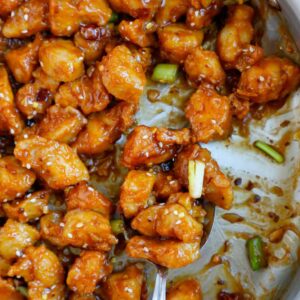 Close up of a spoonful of crispy general tso chicken.