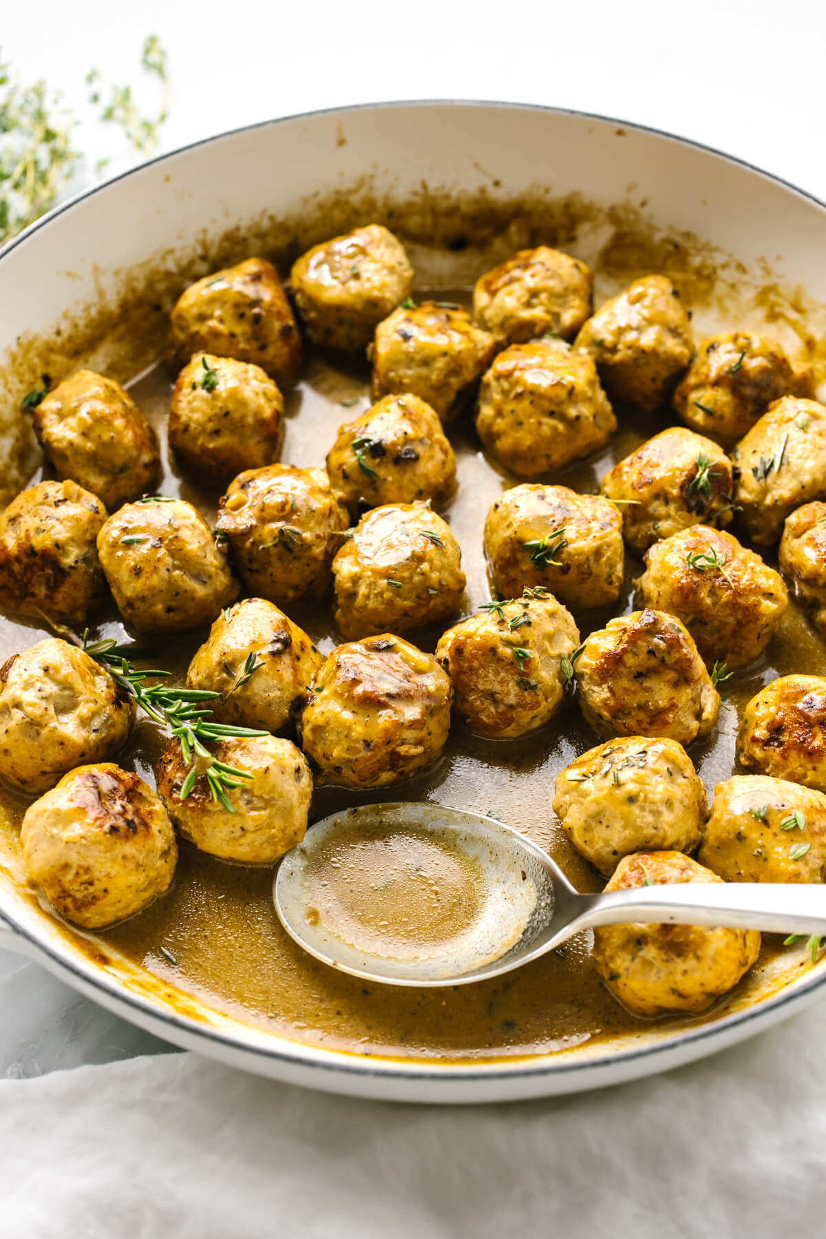 Turkey meatballs in a sauce in a pan with a spoon