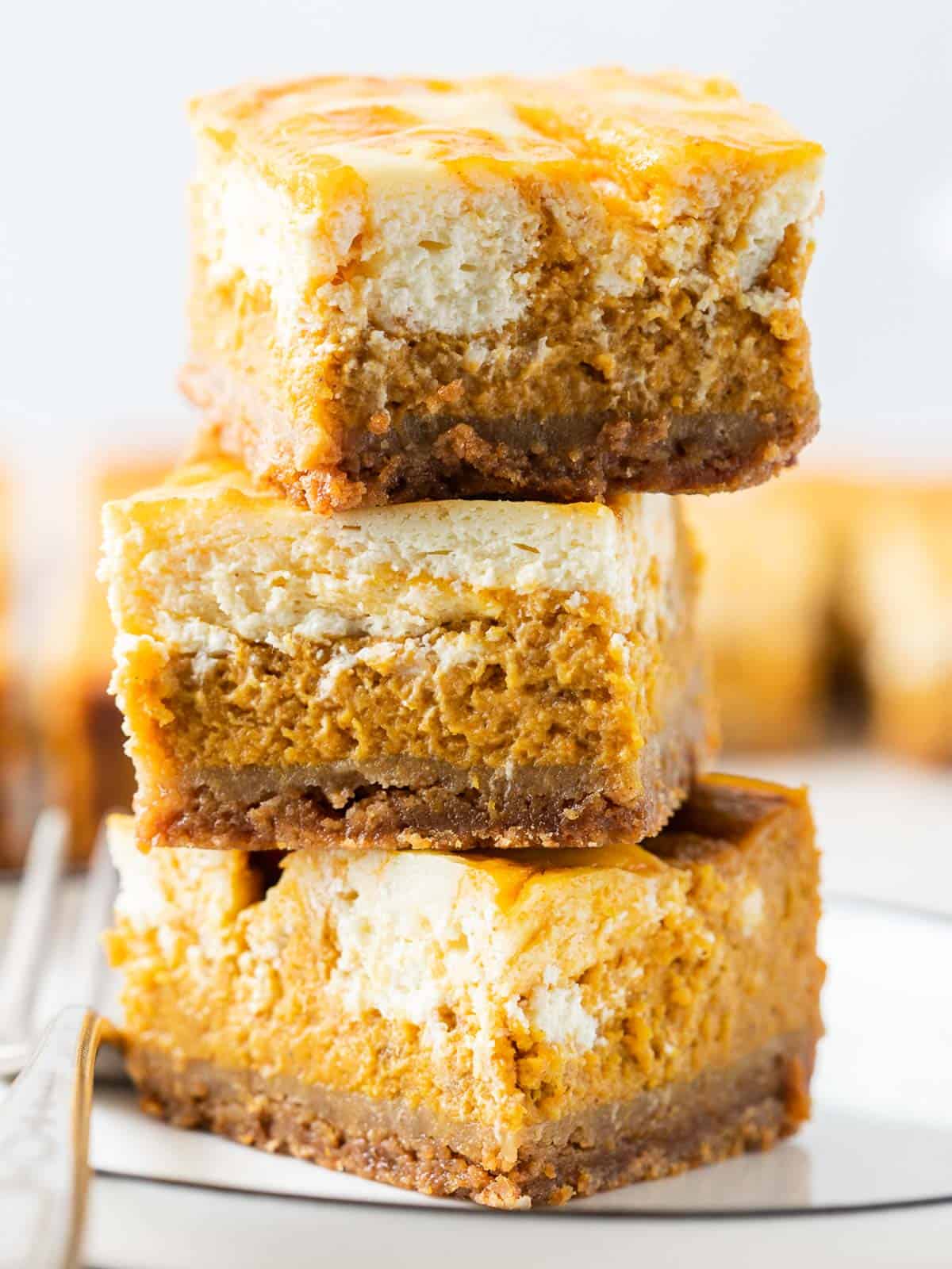 3 stacks of the pumpkin cheesecake bars in a close up shot